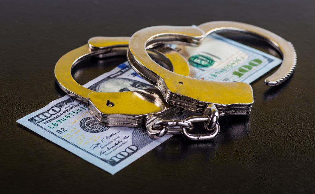 24/7 bail bond concept showing handcuffs on top of a $100 bill