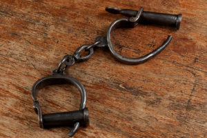 Vintage shackles rest on an old wooden table