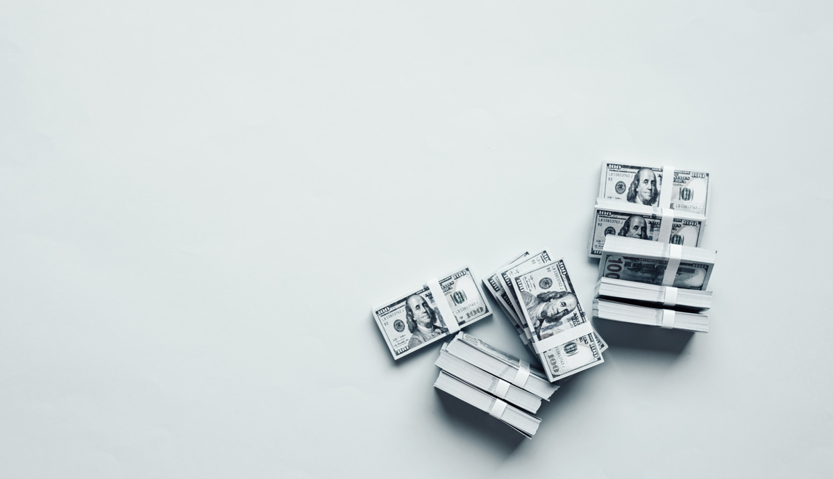 Stacks of cash against a grey background in El Paso.