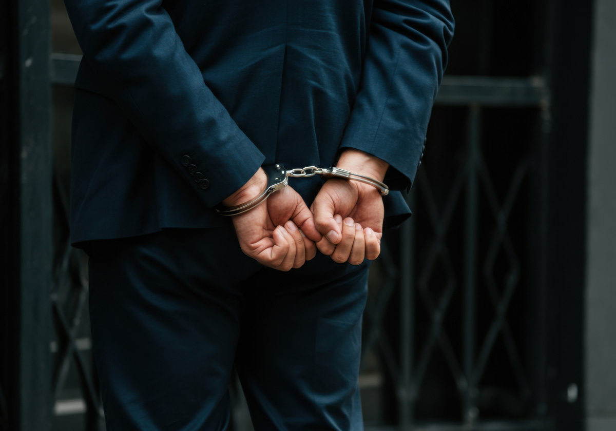 A person in a navy blue suit with their hands handcuffed behind their back in El Paso.